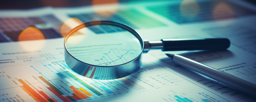 A close-up view of financial documents, graphs, and charts under a magnifying glass, suggesting an analysis of financial data